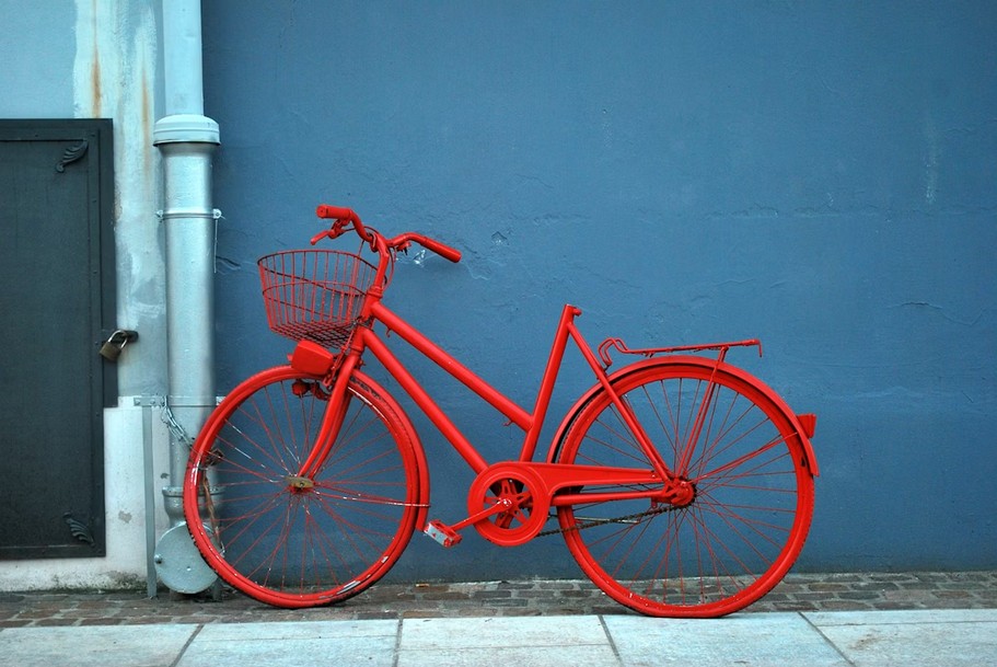 Red city bike parked beside blue painted wall