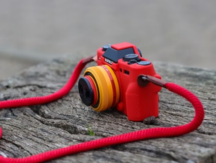 A red camera sitting on top of a piece of wood